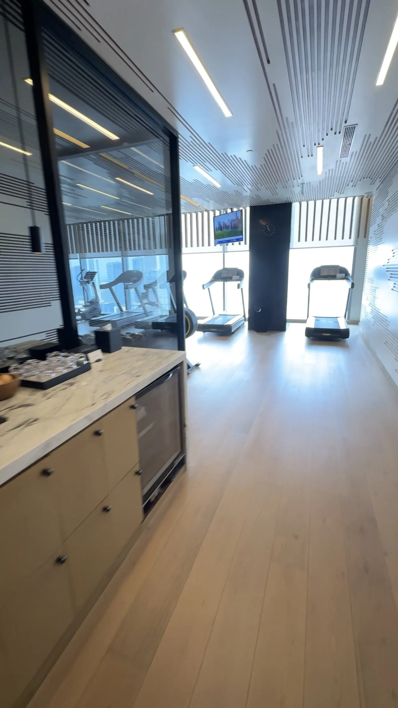 The gym included a refreshment station beside the bright cardio area.